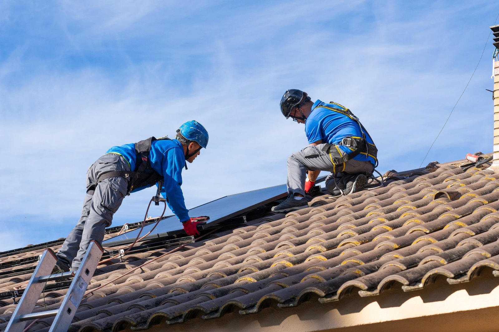 Technicians from AP Sun Energy installing solar panels on a residential rooftop under a bright blue sky, demonstrating professional renewable energy solutions.